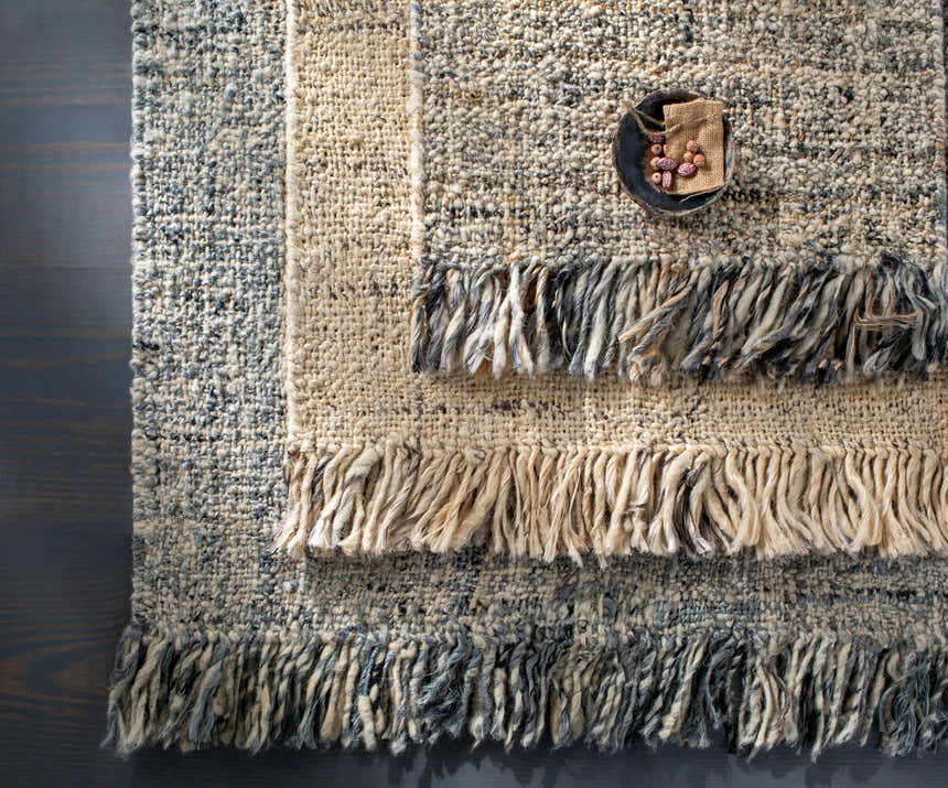 Close-up of the hand woven Edgely Area Rug showing texture, jute, wool, and fringe details in black, gray, beige, and tan. Styleshot