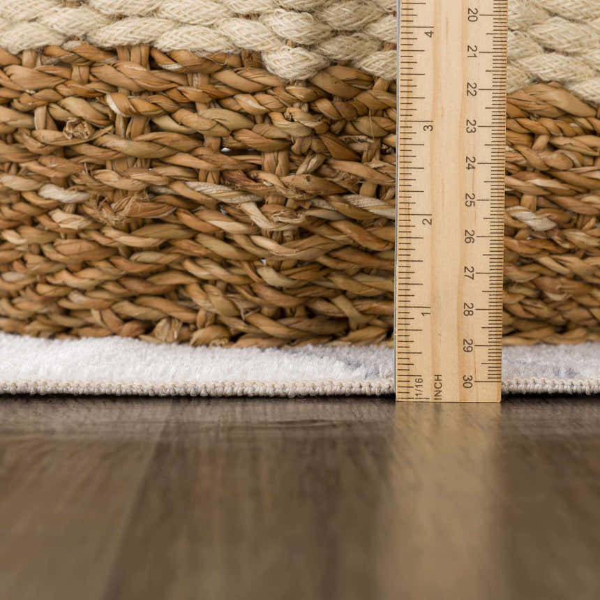 Close-up of the Olwen Washable Area Rug showing the rug's pile height and edge binding next to a ruler. Pile