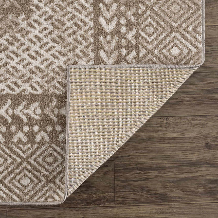 Close-up of the Caditaan Washable Area Rug showing its geometric brown and cream pattern and the rug's backing. Fold