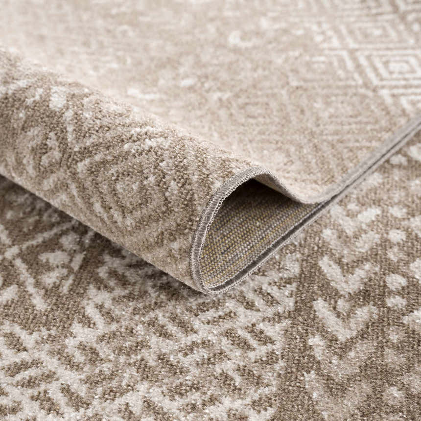 Close-up of the Caditaan Washable Area Rug showing its brown and cream traditional pattern and soft, textured polyester material. Fold