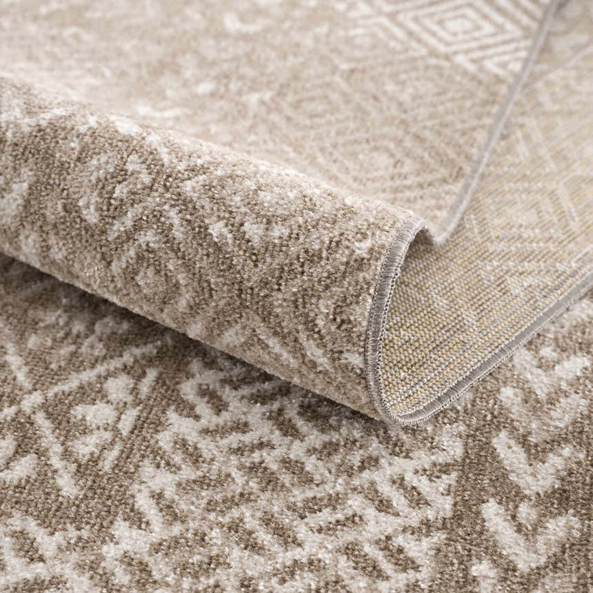 Close-up of the Caditaan Washable Area Rug, showing its brown and cream contemporary pattern and soft, textured polyester material. Fold