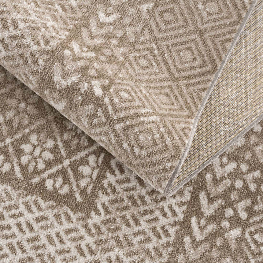 Close-up of the Caditaan Washable Area Rug, featuring a brown and cream geometric pattern and soft, textured polyester. Fold