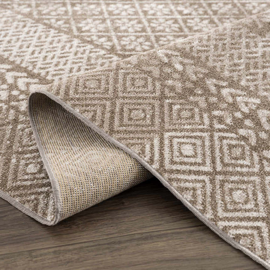 Close up of Caditaan Washable Area Rug showing brown and cream geometric pattern and rug backing on wood floor. Fold