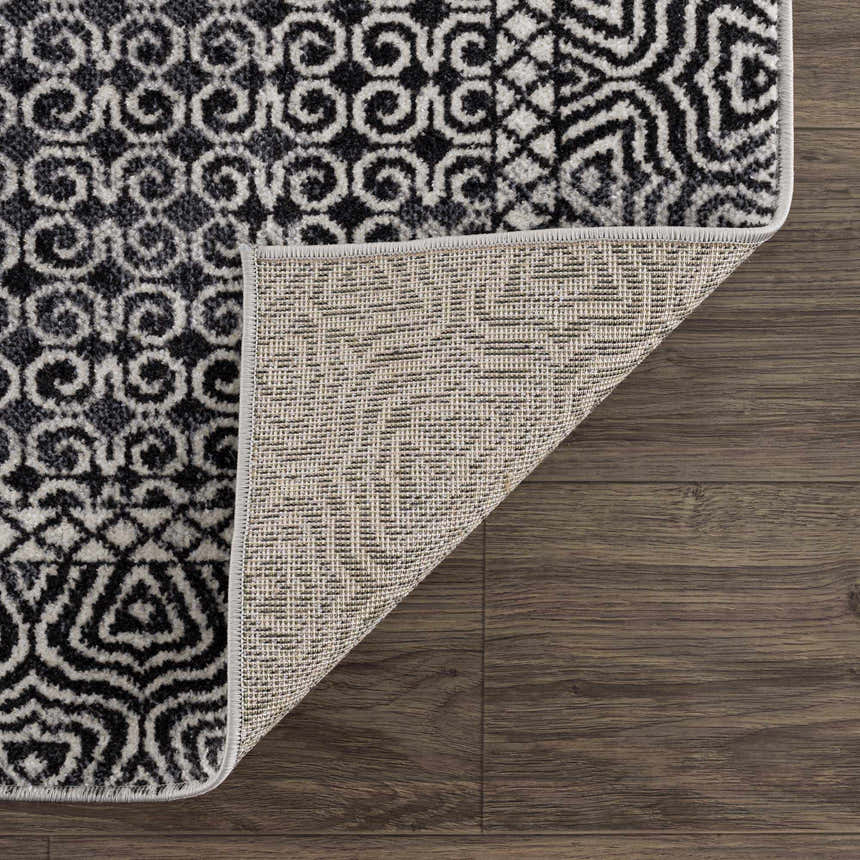 Close-up of the Coledale Black & White Washable Rug showing the geometric pattern, colors, texture, and rug backing. Fold