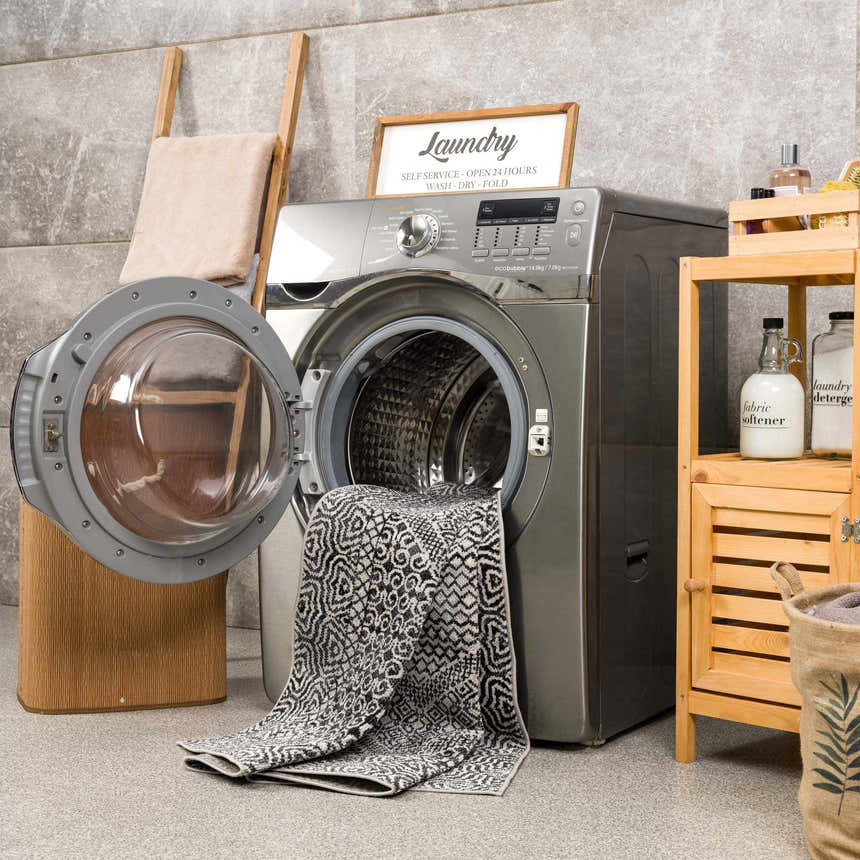 Laundry room scene with Coledale Black & White Washable Rug partially inside a front-load washing machine. Washing-Machine