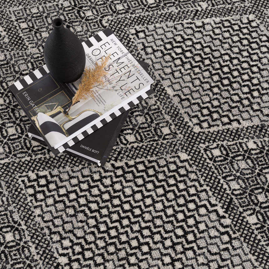 Close-up of the Coledale Black & White Washable Rug with a geometric pattern and soft texture, styled with books and a vase. Styleshot