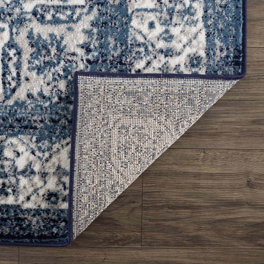 Close-up of the Billy Area Rug showing the blue and white traditional pattern and the rug's backing. Fold