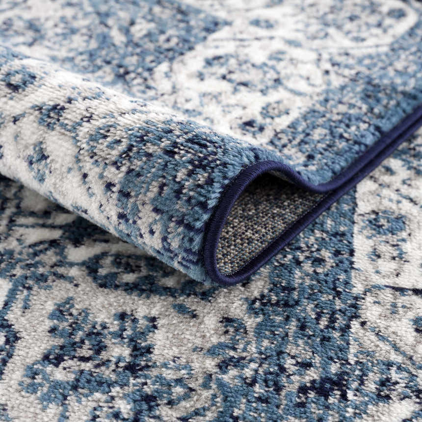 Close-up of the blue and navy Billy Area Rug showing its traditional, Persian-style pattern and machine-woven texture. Fold