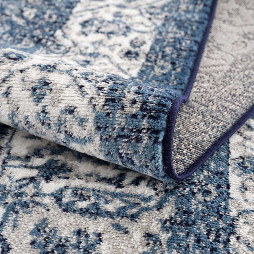 Close-up of the Billy Area Rug showing its blue and navy oriental pattern and soft, textured polypropylene material. Fold