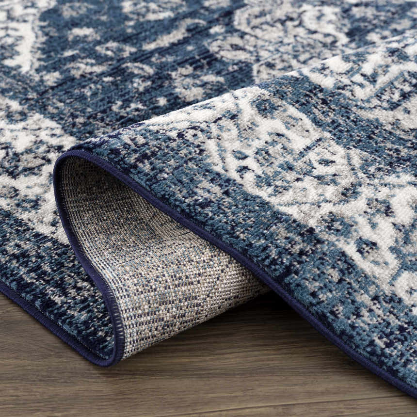 Close-up of the blue and navy Billy Area Rug showing its oriental pattern and machine-woven construction. Fold