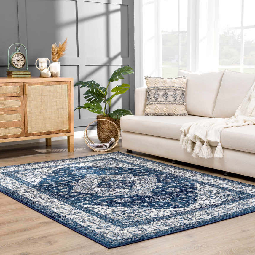 Living room scene with a blue and white Billy Area Rug, beige sofa, and wood cabinet. Roomscene-Rectangle