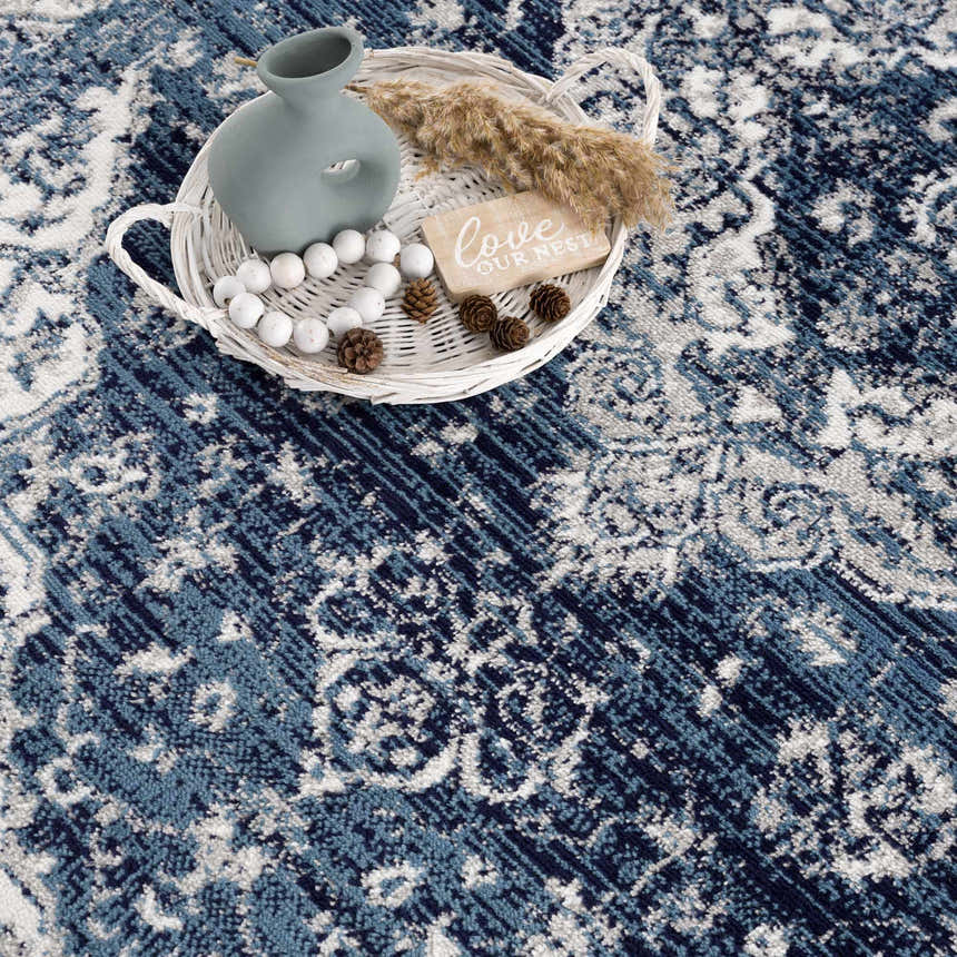 Close-up of the blue and navy Billy Area Rug featuring an oriental, Persian-style pattern and a decorative tray. Styleshot