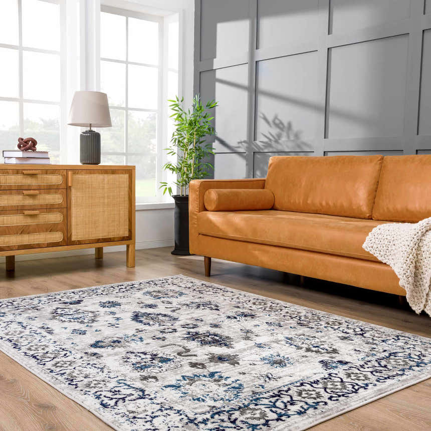 Living room scene with a blue and light gray Duena Area Rug, tan leather sofa, and wood cabinet. Roomscene-Rectangle