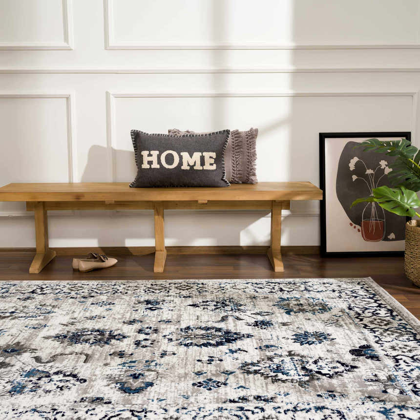 Entryway scene with blue and gray Duena Area Rug, wood bench, pillows, artwork, and houseplant. Roomscene-Rectangle