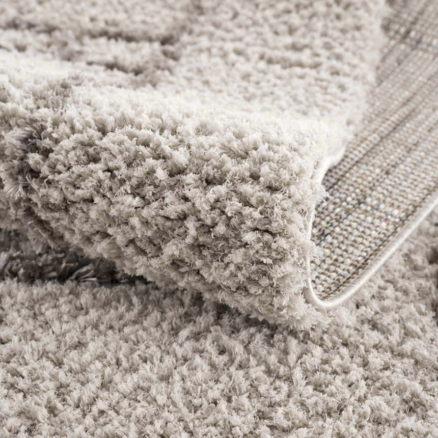 Close up of the textured, silver gray Andia Gray Area Rug, showing shag pile and backing. Fold