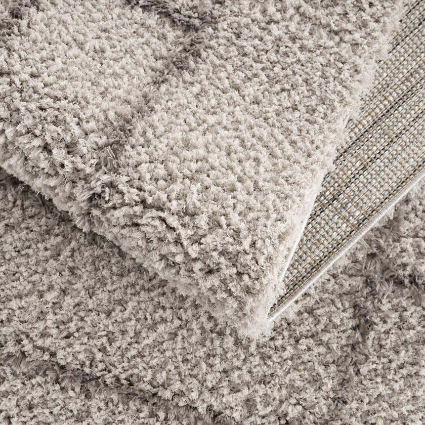 Close-up of the silver gray Andia Area Rug showing its shag texture and machine-woven backing. Fold