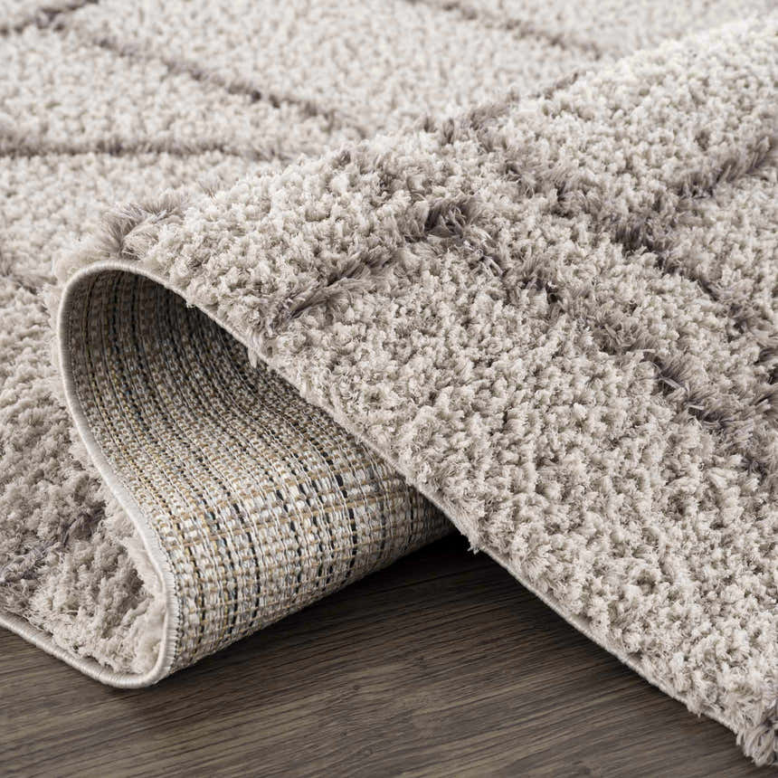 Close up of the Andia Gray Area Rug showing its shag texture and geometric pattern in silver and gray tones. Fold