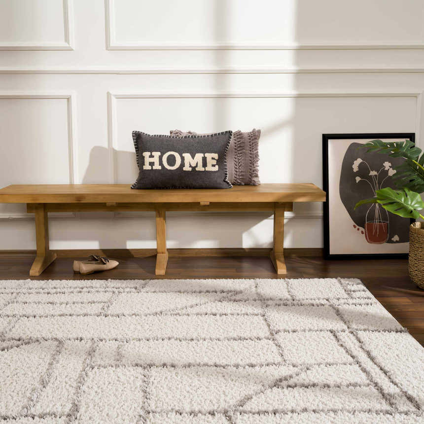 Entryway scene with a wooden bench, gray HOME pillow, and the Andia Gray Area Rug. Roomscene-Rectangle