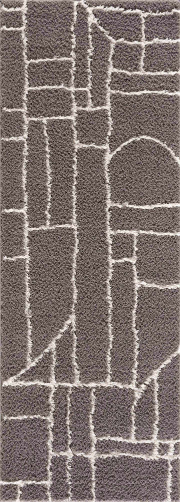 Close-up of the Andia Charcoal Area Rug. Gray shag rug with a geometric pattern of white lines and shapes. Design-Runner