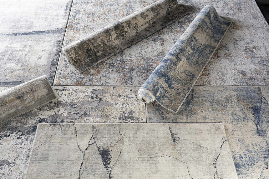 Close-up of Ryhill Textured Luxe Area Rug showing charcoal, blue, beige, and gray abstract patterns and rolled texture. Styleshot