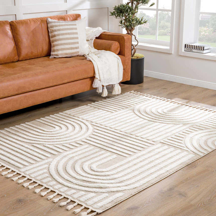 Living room scene with a beige Moise Area Rug, tan leather sofa, and natural light from a window. Roomscene-Rectangle