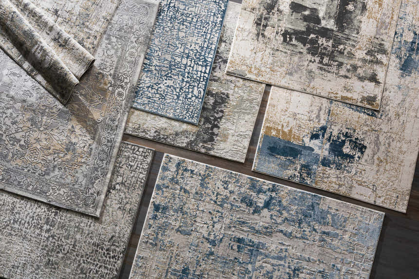 Assorted Kiana Area Rugs in contemporary styles, featuring blue, gray, and neutral tones with abstract and traditional patterns. Styleshot