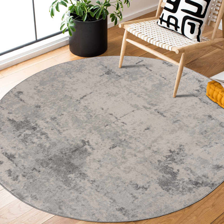 Living room scene with a round Tigrima Ivory 2319 Area Rug, wood floors, chair, and plant creating a cozy, contemporary vibe. Roomscene-Round
