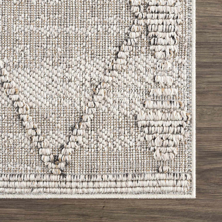Close-up of Nyla Bone rug showing textured weave, geometric pattern, and bone color on dark wood floor. Contemporary style. Swatch