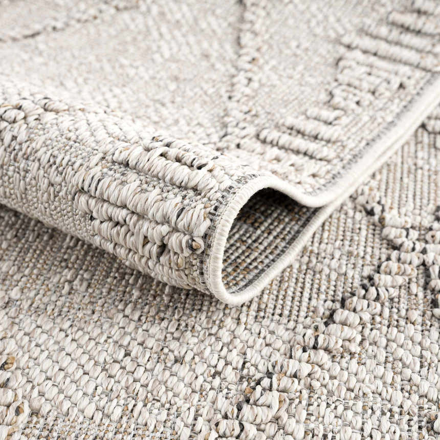 Close-up of the Nyla Bone Indoor Outdoor Rug showing its woven texture and geometric pattern in neutral bone tones. Fold