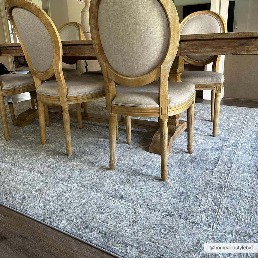 Dining room scene with a light wood table and chairs on the Ulubey Distressed Gray Thick Luxe Area Rug. Roomscene-Rectangle