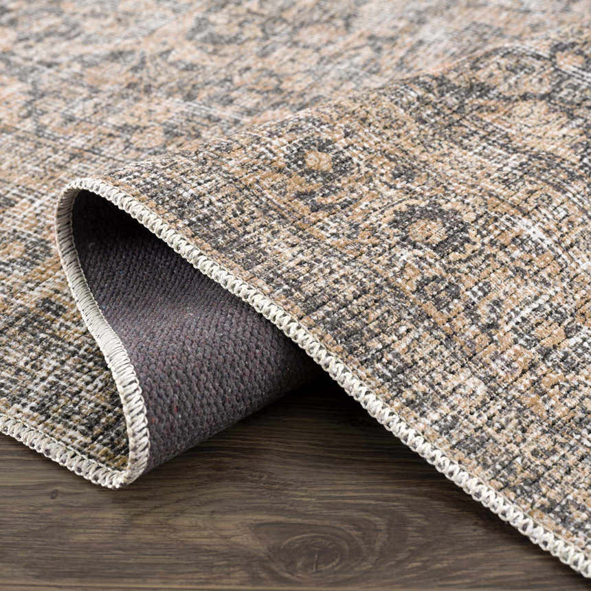 Close-up of the Orsin Washable Area Rug showing its farmhouse traditional design, neutral colors, and textured weave. Fold