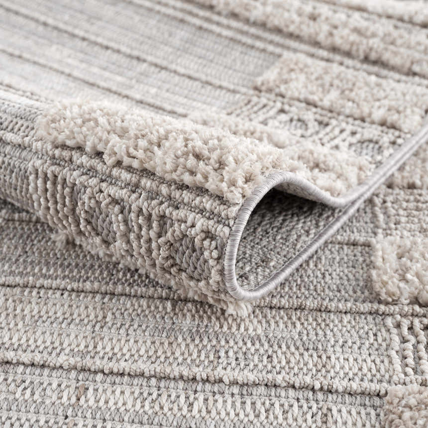 Close-up of the Sulak Cream Area Rug showing the textured, geometric pattern and soft pile. Neutral colors. Fold