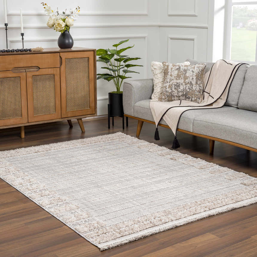 Living room scene with a Sulak Cream Area Rug, gray sofa, wood cabinet, and neutral decor. Roomscene-Rectangle