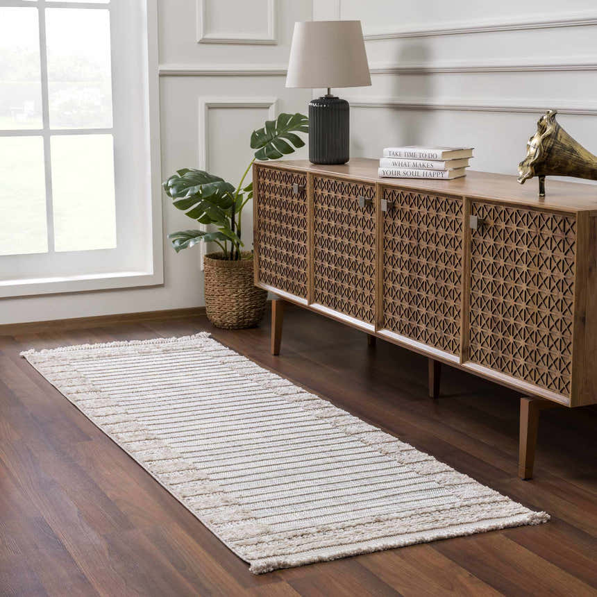 Entryway with a Sulak Cream Area Rug, wooden console table, lamp, and monstera plant. Roomscene-Runner