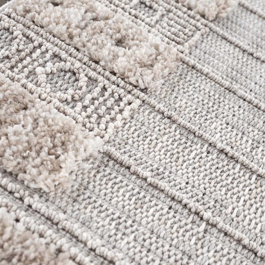 Close-up of the Sulak Cream Area Rug showing its textured weave and cream-colored tufted details. Texture