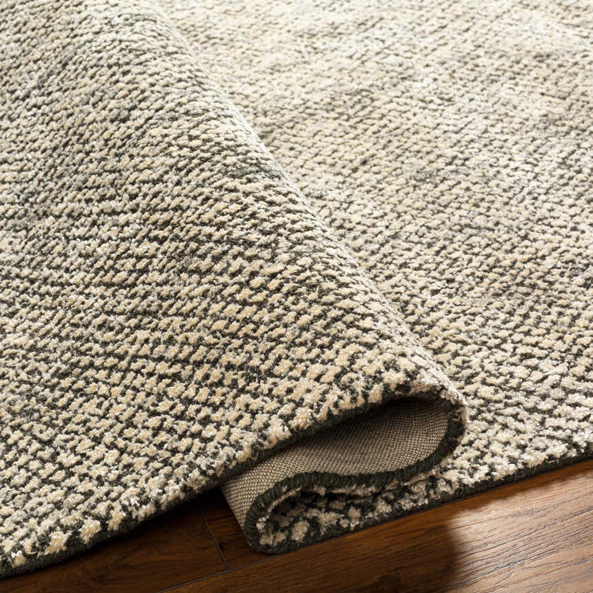 Close-up of the Abiba Area Rug showing its beige and black textured, hand-loomed design and wool-viscose blend. Fold