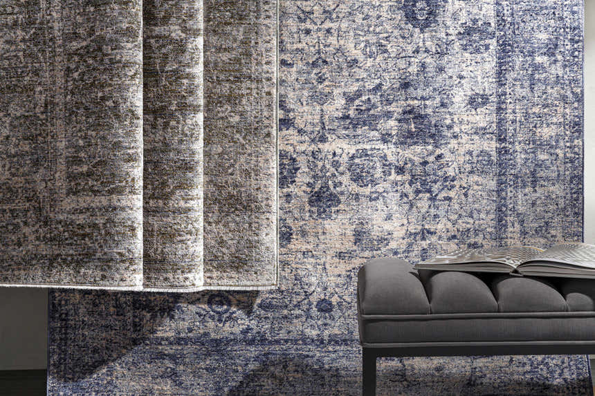 Close-up of the Accokeek Luxe Area Rug in denim, light beige, and navy, styled with a gray bench and open book. Styleshot