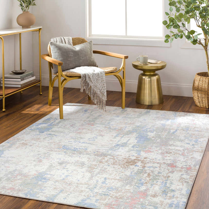 Living room scene with the Ahava Washable Area Rug. White rug with blue, pink, and tan accents. Modern chair and gold accents. Roomscene-Rectangle