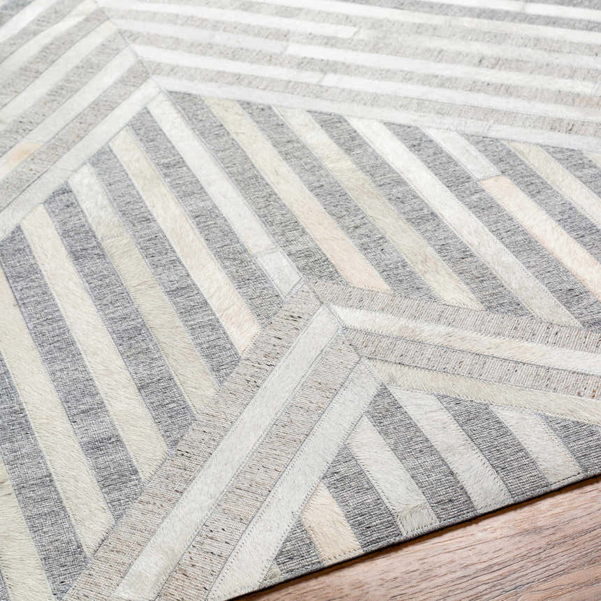 Close-up of the Akiye Area Rug, a geometric design in beige, cream, and gray leather and viscose. Fold