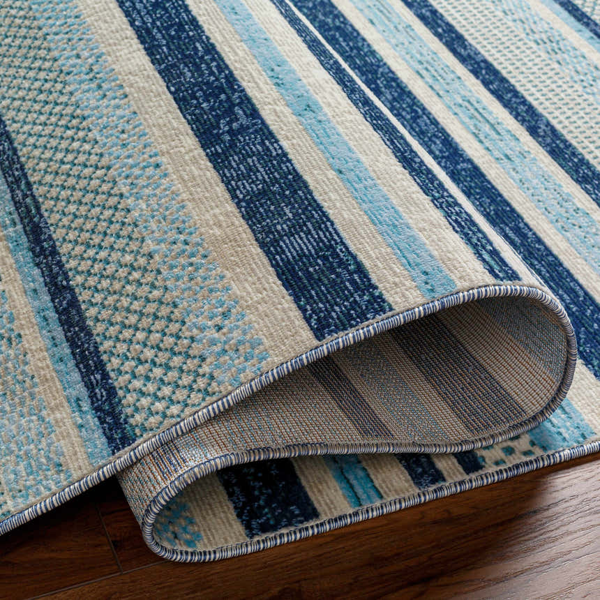 Close-up of the Alain Area Rug showing a coastal geometric pattern in shades of blue and beige. Fold