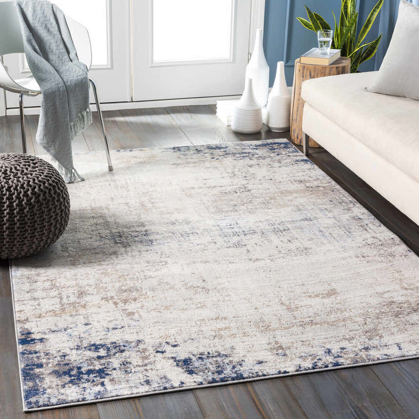 Living room scene with Alcove Abstract Area Rug in dark blue, gray, and ivory. Modern decor with sofa, chair, and wood floors. Roomscene-Rectangle