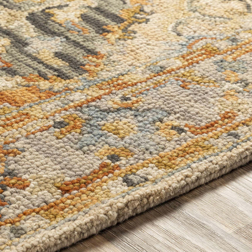 Close-up of the hand-tufted Alliance Area Rug. Features an intricate pattern in beige, gray, gold, and blue hues. Texture