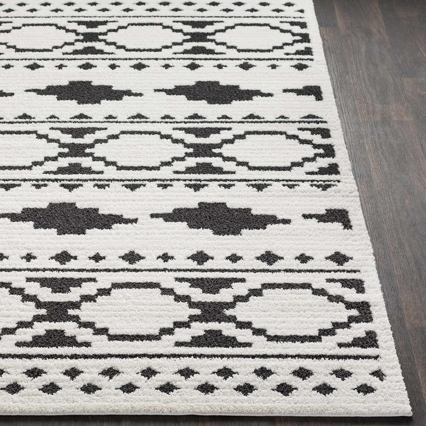 Close-up of Amoret Area Rug showing black geometric pattern on off-white, textured pile. Front