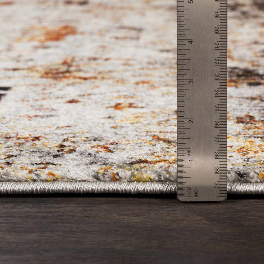 Close-up of Analisa Area Carpet showing pile height with ruler. Colors: ivory, orange, black. Machine woven construction. Pile