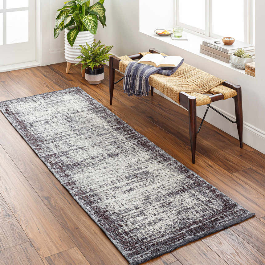 Entryway with Binh Gray Area Rug runner, wood floors, and a woven bench with open book near a window. Roomscene-Runner