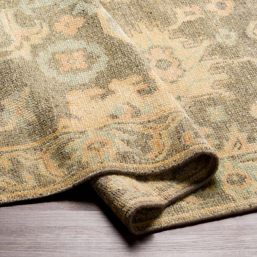 Close-up of the hand knotted Asotin Area Rug. Wool rug with burnt orange, charcoal, mustard, olive, and seafoam colors. Fold