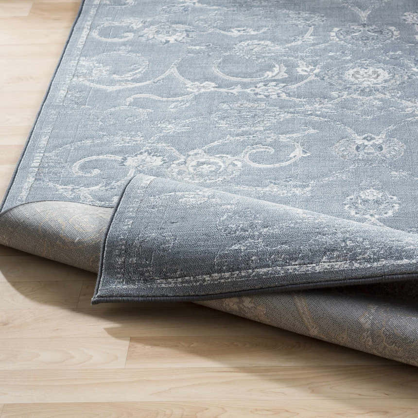 Close-up of the Astatula Area Rug, a machine-woven rug in blue, ice blue, and ivory with a traditional floral pattern. Fold