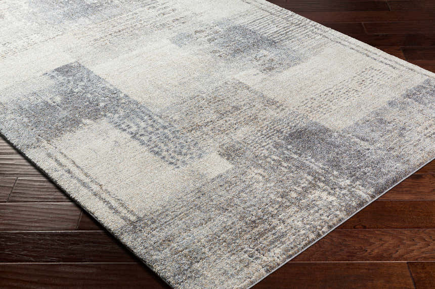 Close-up of the Bacca Area Rug showing its gray, light gray, and nutmeg contemporary pattern and machine woven texture. Corner