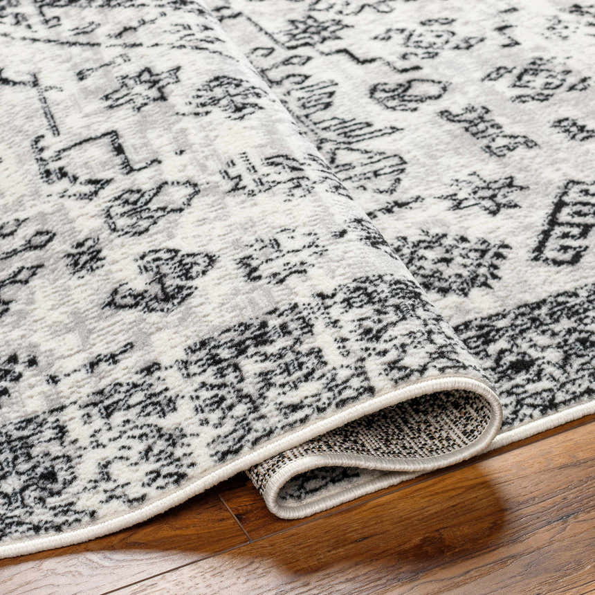 Close up of the Badar Area Rug showing its charcoal and gray traditional pattern. Fold