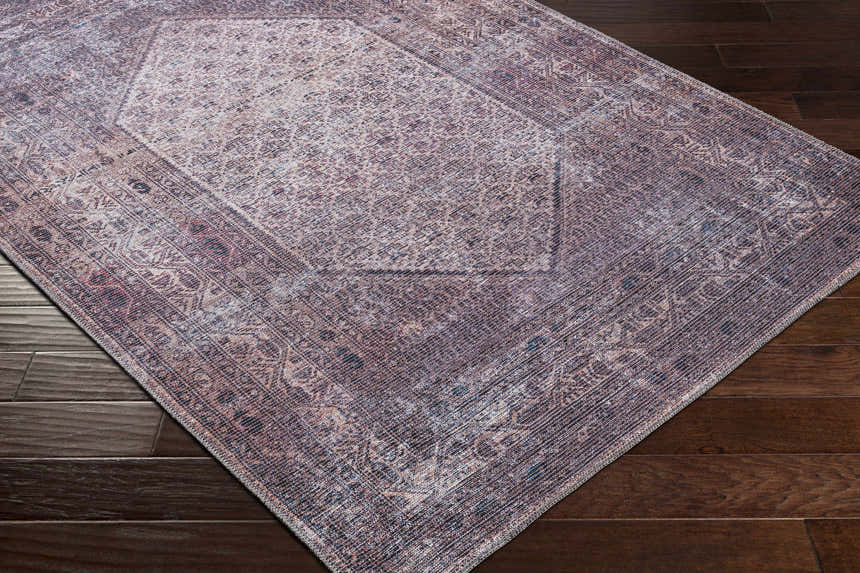 Close-up of the Dusty Pink Bagacay Distressed Washable Area Rug showing its oriental pattern and colors on a dark wood floor. Corner